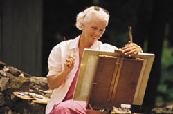 An image of an elderly woman painting outside